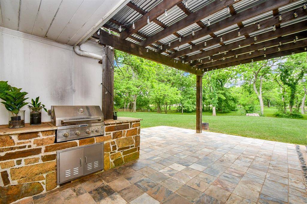 Travertine patio with covered pergola, built in grill with natural stone surround