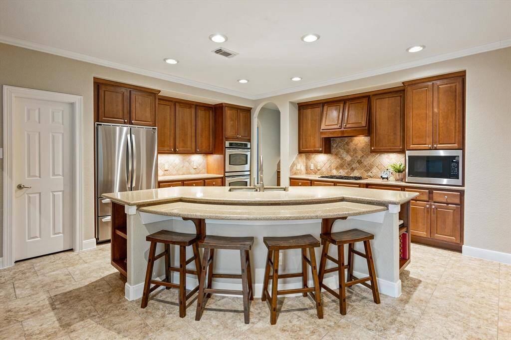 Rich, natural wood cabinetry offers abundant storage while seamlessly complementing the warm tones of the granite countertops and the sophisticated stone tile backsplash.