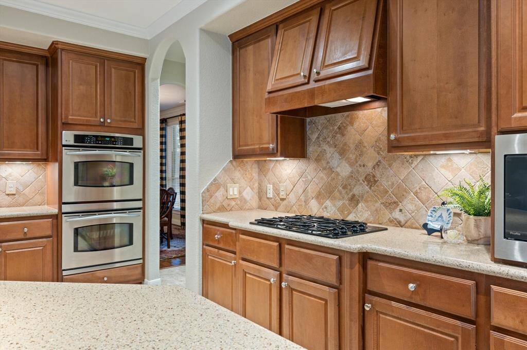 A suite of high-end stainless steel appliances—including a built-in microwave, gas cooktop, and double ovens—ensures that meal preparation is efficient and enjoyable.