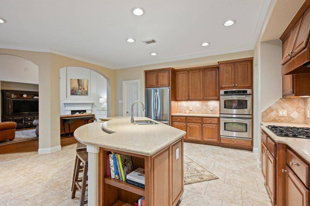 The expansive center island is both functional and stylish, featuring an undermount sink and extended breakfast bar that invites casual dining, conversation, or a quick morning coffee.