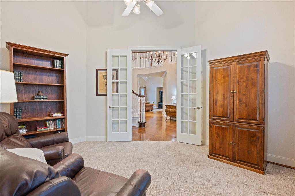 A ceiling fan ensures year-round comfort, while plush carpeting adds warmth underfoot. Crown molding lends a refined touch, and large windows fill the room with soft, natural light—creating an inspiring environment for any task.
