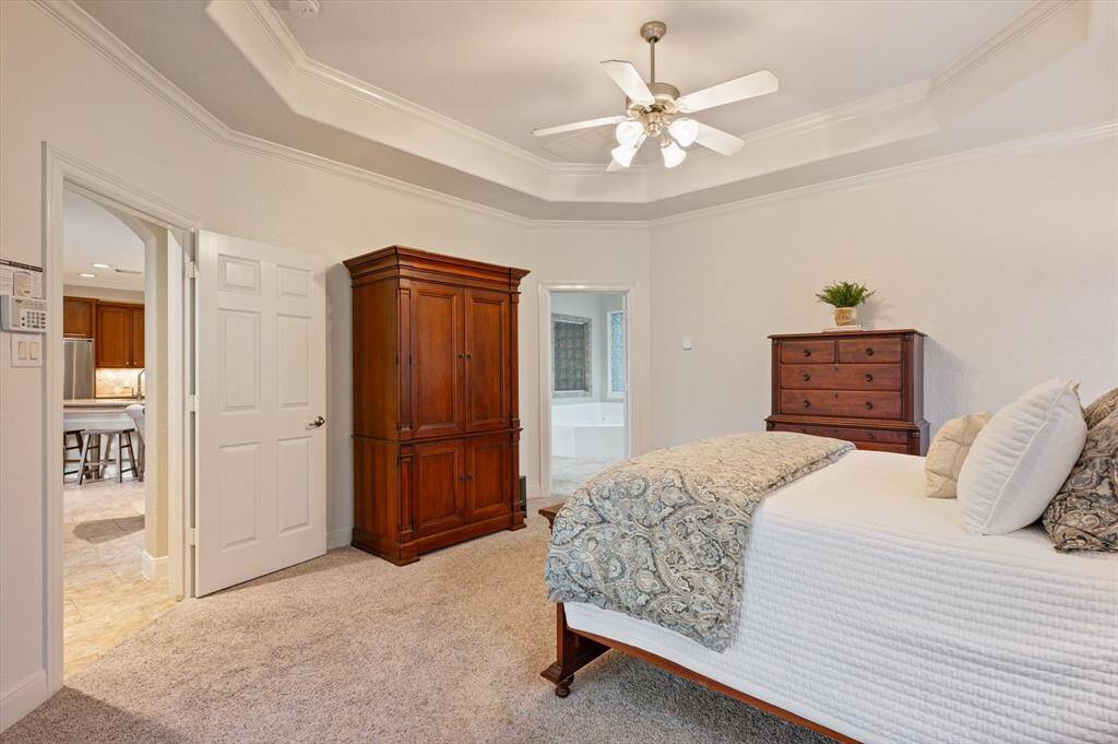 A sophisticated tray ceiling adds architectural interest and height to the room, while plush carpet underfoot creates a cozy, inviting atmosphere. Bathed in natural light during the day and softly lit in the evening, this primary retreat offers the ideal balance of beauty and functionality.