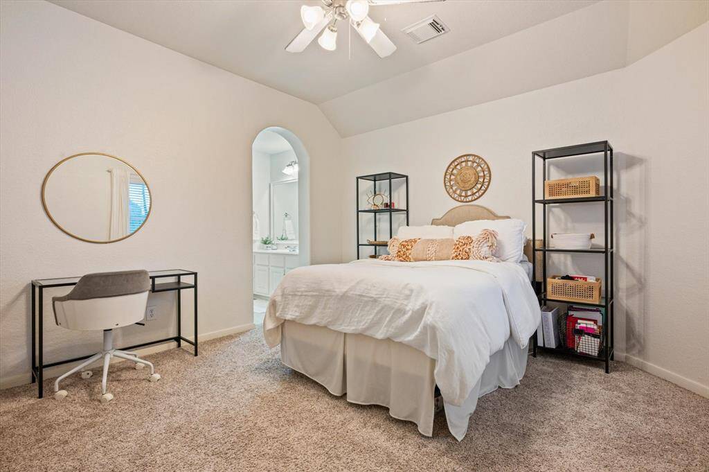 This second spacious upstairs secondary bedroom features a high ceiling with a ceiling fan, plush carpeting, and a large window that fills the room with natural light. It also offers the convenience of direct access to a jack and jill bathroom.
