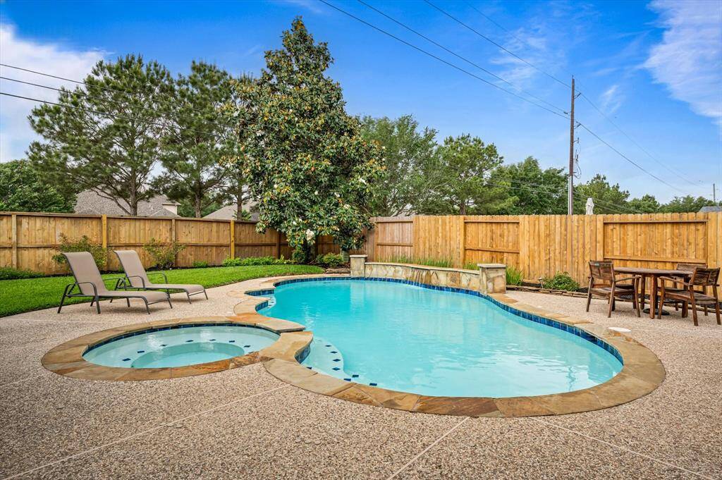Surrounding the pool, an expansive pebblestone patio adds texture and elegance, offering plenty of room for sunbathing, outdoor seating, or setting up a grill station.