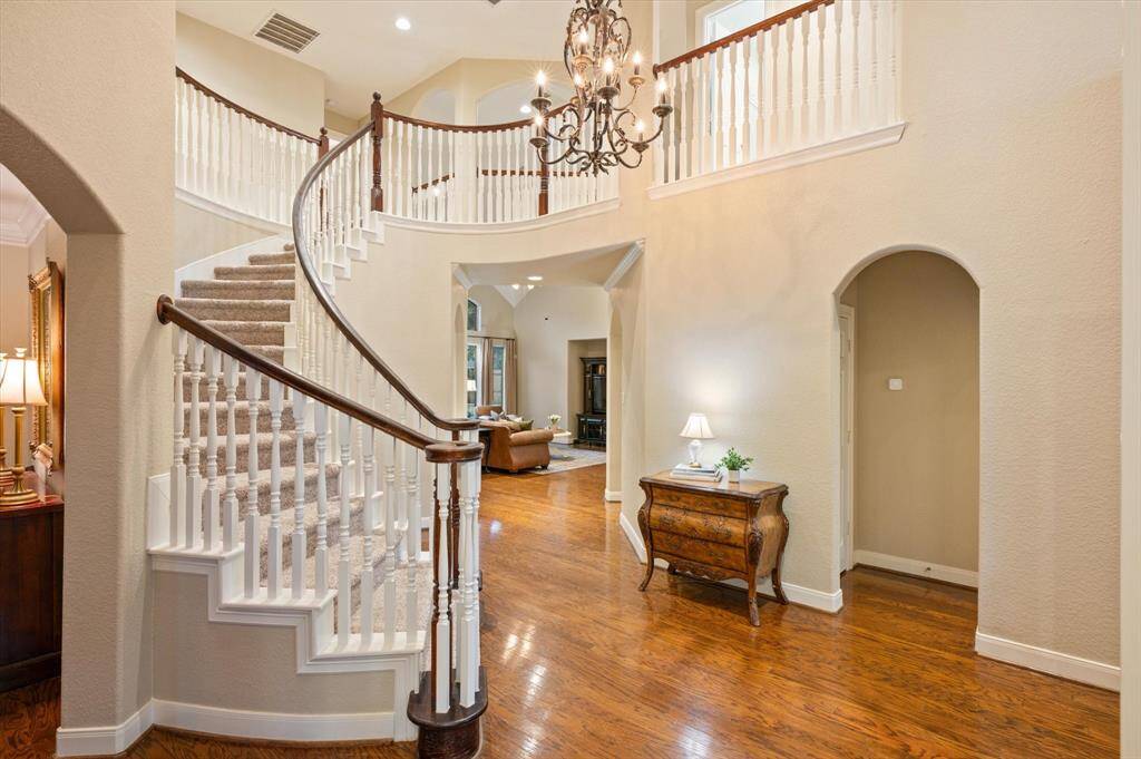 Step inside to be greeted by an inviting and open foyer, where gleaming wood floors stretch throughout the main living areas, adding warmth and sophistication. Soaring ceilings create a sense of space and grandeur, while an elegant curved staircase serves as a striking focal point that sets the tone for the rest of the home.