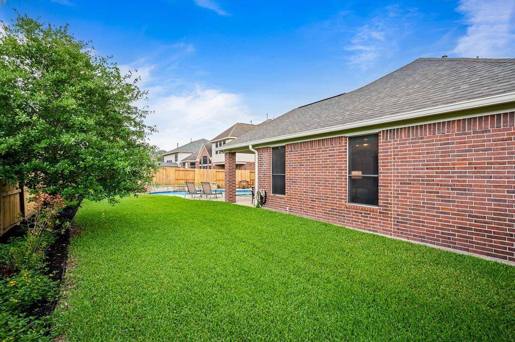 Beyond the patio, a generous stretch of lush green lawn provides ample space for children and pets to run and play, making this backyard ideal for both relaxation and recreation.