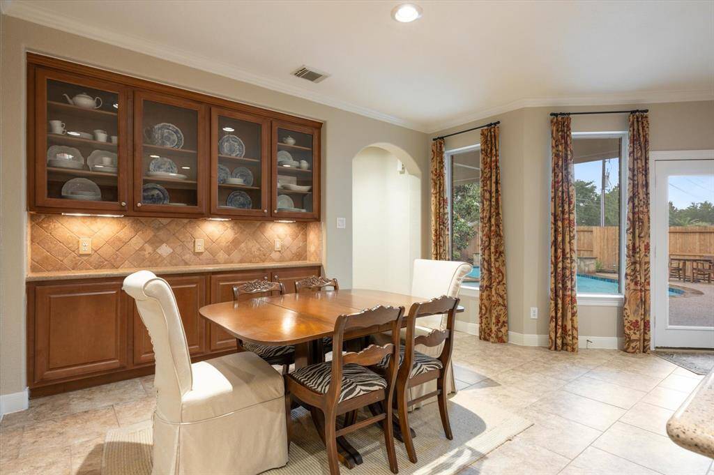 Large windows flood the breakfast room with natural light, creating a warm and inviting atmosphere, while crown molding adds a touch of elegance.