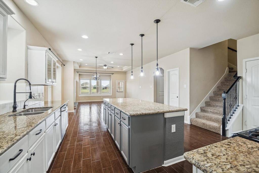 Designed for both function and connection, this open-concept kitchen features an oversized island with bar seating that creates a natural hub for conversation, casual dining, and entertaining. Complete with crisp white cabinetry, sleek granite countertops, tile backsplash, and stainless steel appliances, this kitchen seamlessly blends style and practicality in a layout that keeps you connected to family and guests.