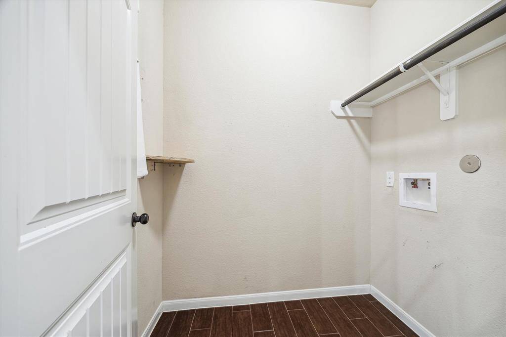 The utility area offers durable wood-look tile flooring, neutral paint, a hanging bar for clothes and both gas and electric dryer connections.