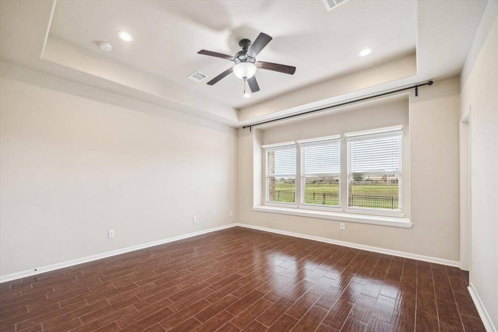 You’ll have sweet dreams in this serene owner’s retreat, featuring wood-look tile flooring, soft neutral tones, and a raised tray ceiling. A wall of windows offers peaceful lake views, while the massive walk-in closet and luxurious ensuite bath complete the space with both comfort and style.