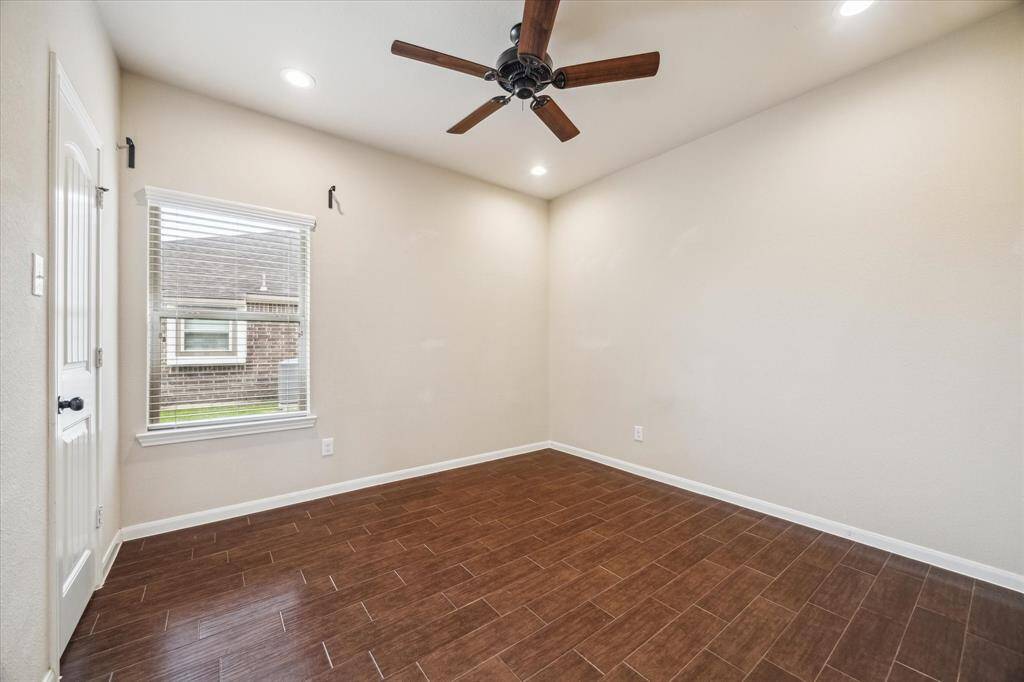 This first-floor guest bedroom offers comfort and versatility with wood-look tile flooring, neutral paint, a ceiling fan, and a spacious closet. With easy access to a full bath featuring a walk-in shower, it’s ideal for overnight guests or can flex as a home office, gym, yoga studio, or creative space.