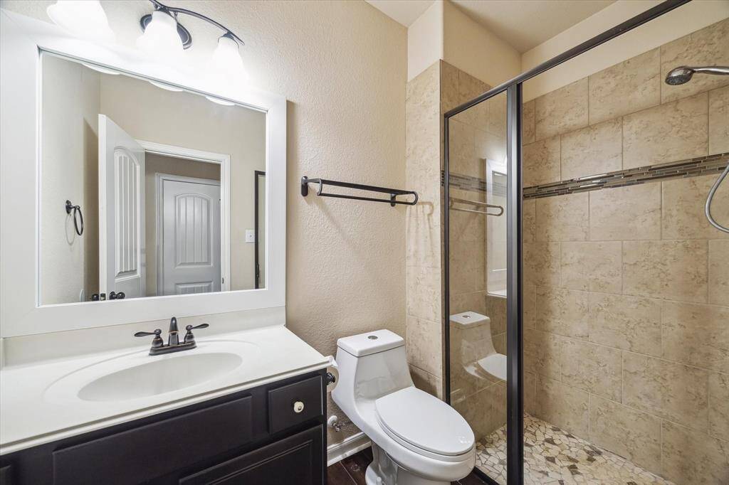 The first-floor guest bathroom offers convenience and style with a sleek vanity, framed mirror, and modern lighting. A fully tiled walk-in shower with mosaic flooring and a glass enclosure adds a touch of luxury for overnight guests or daily use.