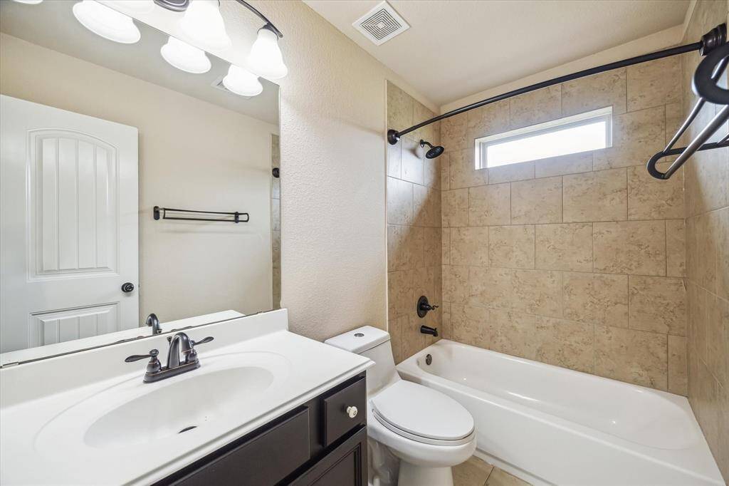 This is the second of two full bathrooms upstairs. This bathroom offers tile flooring and a fully tiled tub/shower enclosure plus a single sink vanity with a full mirror and vanity lights above.