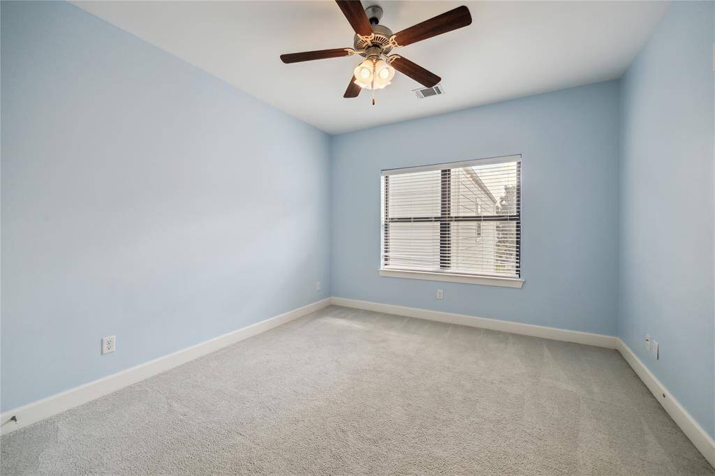 One of two guest bedrooms with window blinds, ceiling fan, and generous closet space.