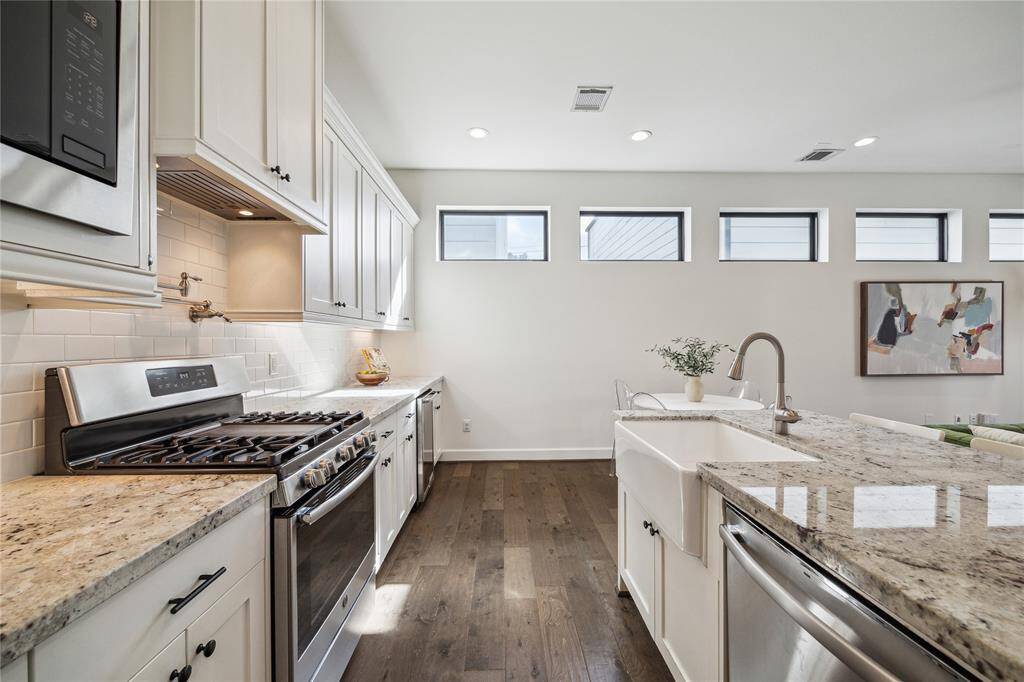 Beautiful view of the kitchen showing the gas range, farmhouse sink, expansive counter space, and a ton of storage options.