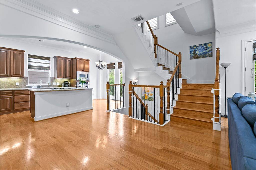 Open-concept layout, this home showcases soaring ceilings, sleek hardwood floors, a kitchen island with built-in cooktop
