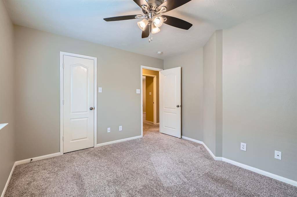 Bright, cozy bedroom with soft carpet, neutral walls, ceiling fan.