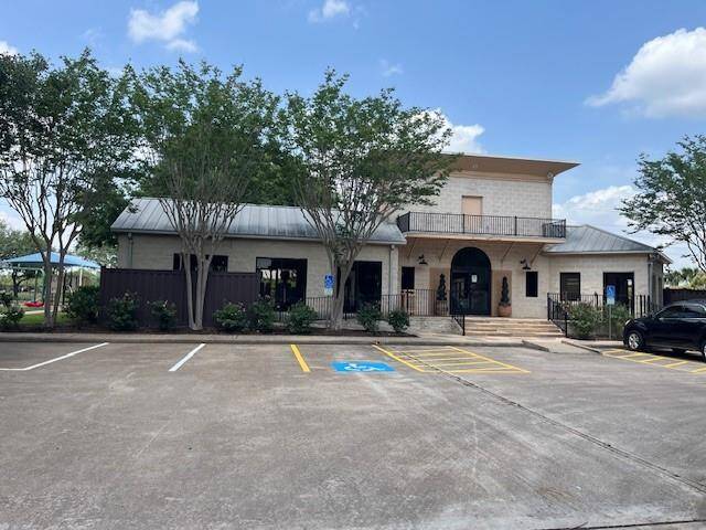 The Club House, modern two-story building with a metal roof and balcony. Inside boast an exercise/ workout facility with gym equipment. Surrounded by trees, it features a spacious parking area with designated accessible parking spaces.