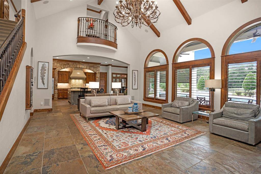 Expansive and elegant, the living room showcases arched windows, slate floors, and a stunning two-story ceiling.