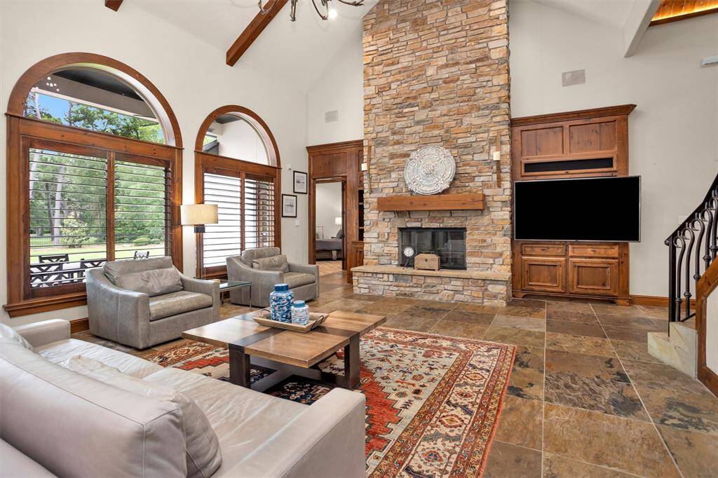 Gather around the dramatic floor-to-ceiling stone fireplace in a living room designed for both comfort and grandeur.