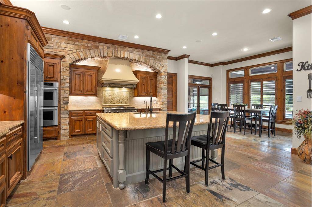 The heart of the home shines with a chef-inspired kitchen featuring a spacious island, custom wood cabinetry, and sunny breakfast nook.
