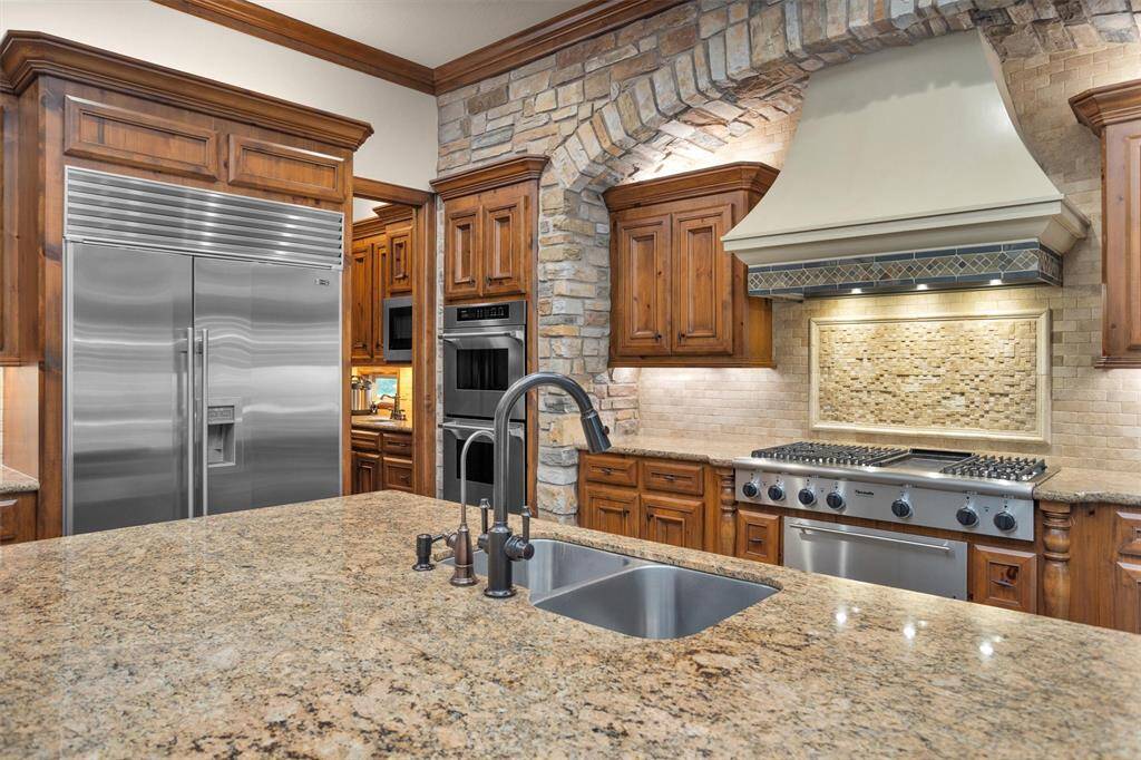 Cook in style with a professional Thermador gas range, stone arch detail, and built-in double ovens fit for any culinary enthusiast.