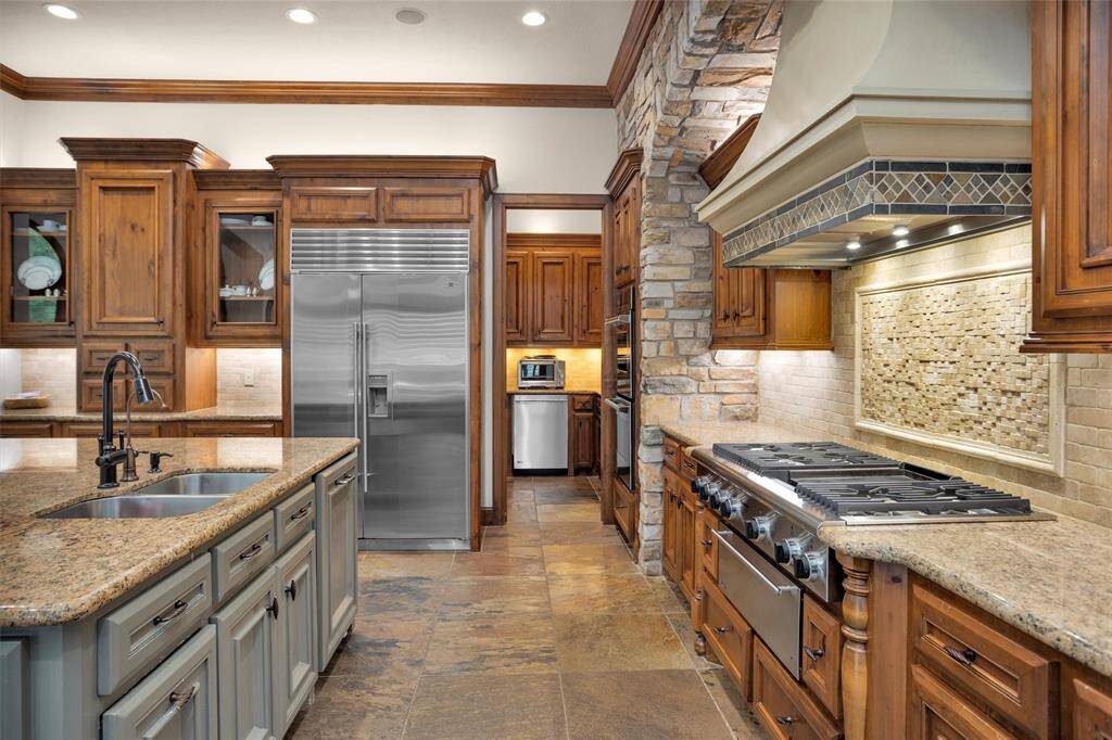 Top-tier Sub-Zero refrigerator and custom cabinets pair beautifully with warm stone and granite finishes throughout the kitchen.