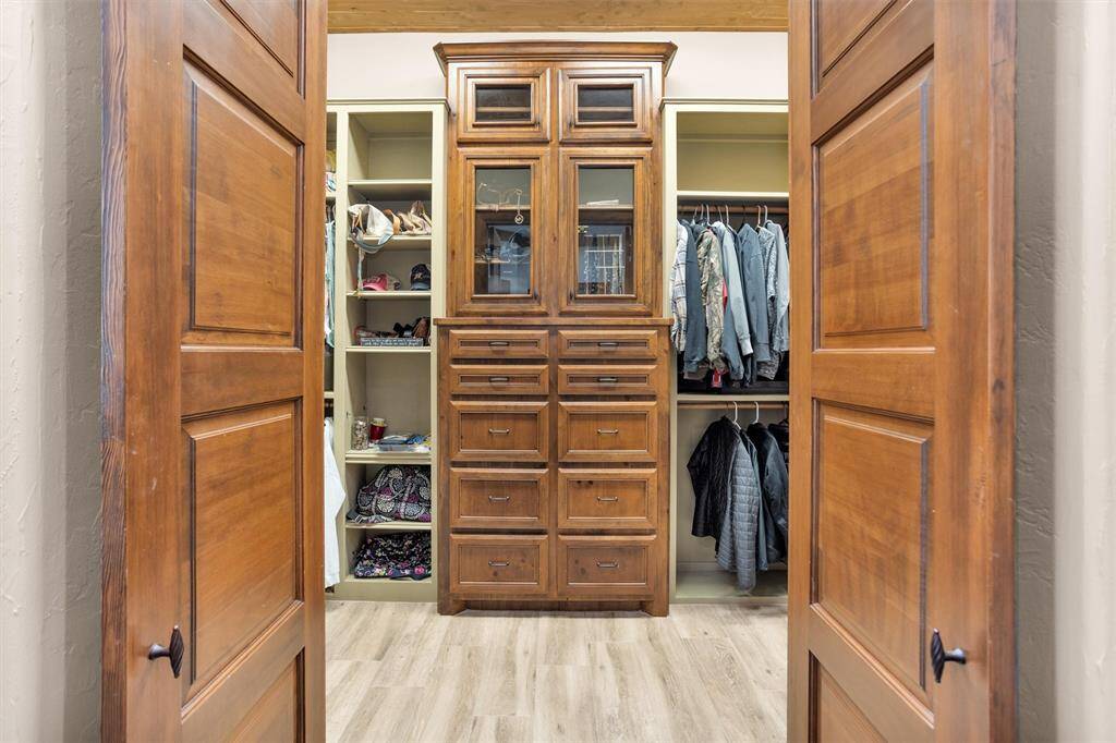 The primary closets are a true showpiece—equal parts form and function. Custom cabinetry, deep drawers, and glass-front shelving create a beautifully organized space, while a built-in ladder leads to ceiling-height storage. Open shelving offers ample room for shoes, bags, and seasonal pieces, and a full-length mirror with tri-fold panels and a built-in bench adds a boutique-style finishing touch. With two thoughtfully designed closets, storage is never an afterthought.