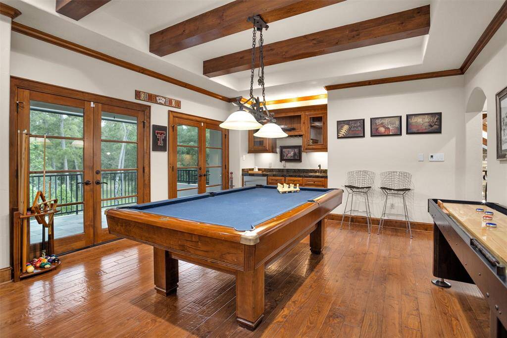 The upstairs game room includes a pool table, bar with sink, shuffleboard, and access to a private balcony—ideal for entertaining.