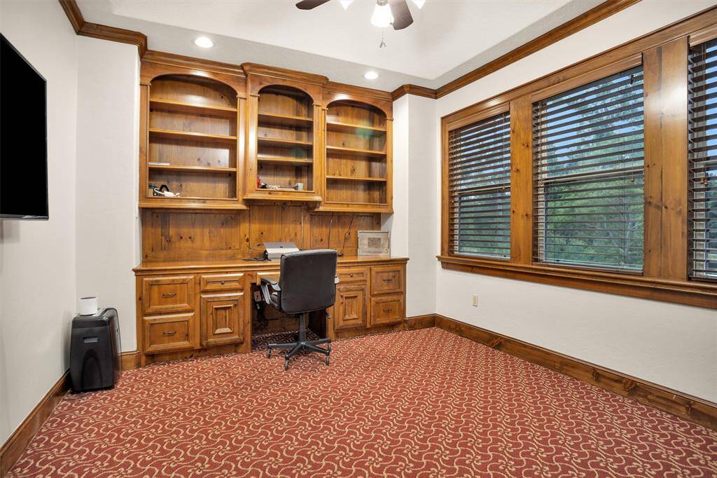 This upstairs office includes built-in shelving, drawers, and a large workspace surrounded by windows overlooking the treetops.