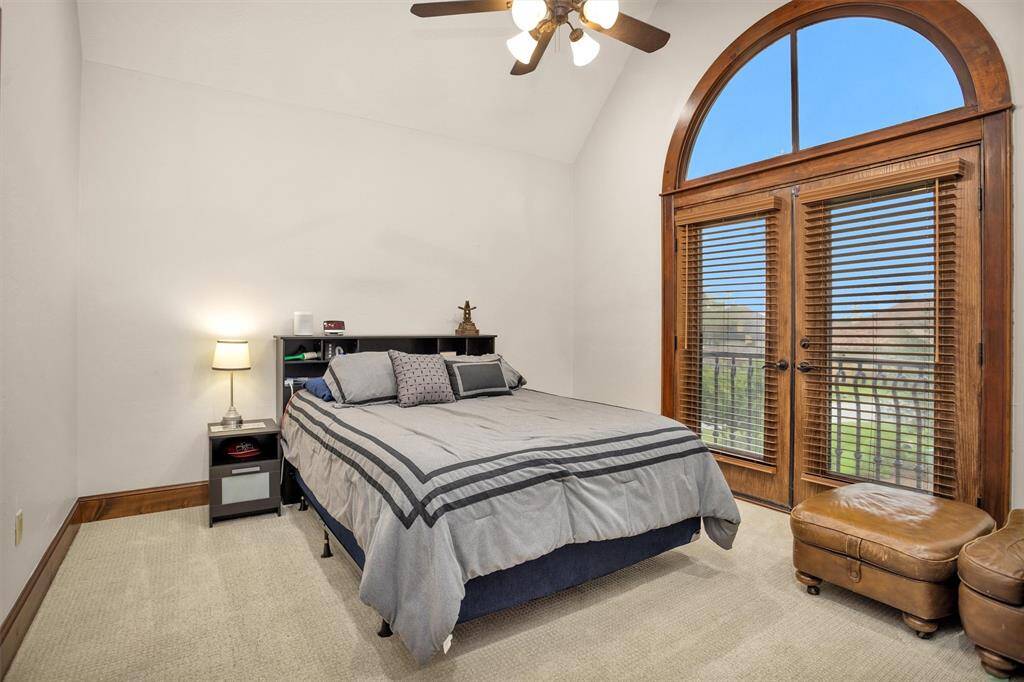 Vaulted ceilings and arched glass doors give this upstairs secondary bedroom a grand yet cozy feel, complete with private balcony views.