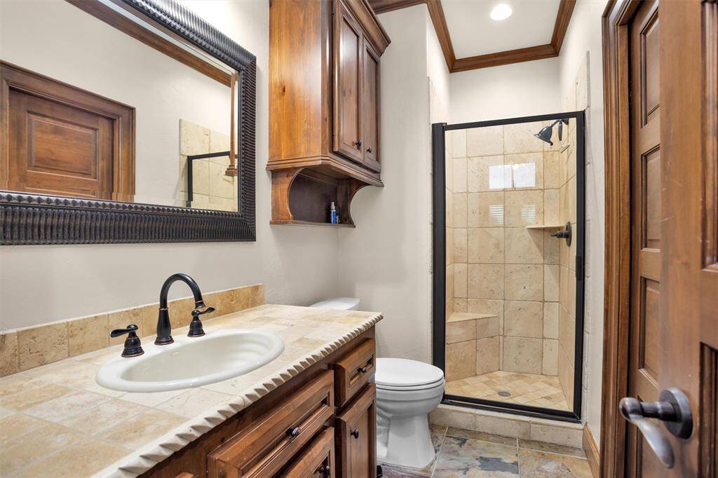 A charming ensuite with framed mirror, rich cabinetry, and tiled walk-in shower offers guests both comfort and sophistication.