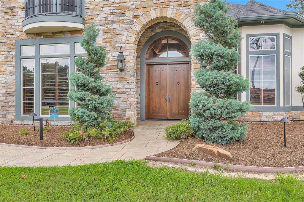 Stately double front doors beneath a stone archway welcome you into this custom masterpiece with warmth and sophistication.