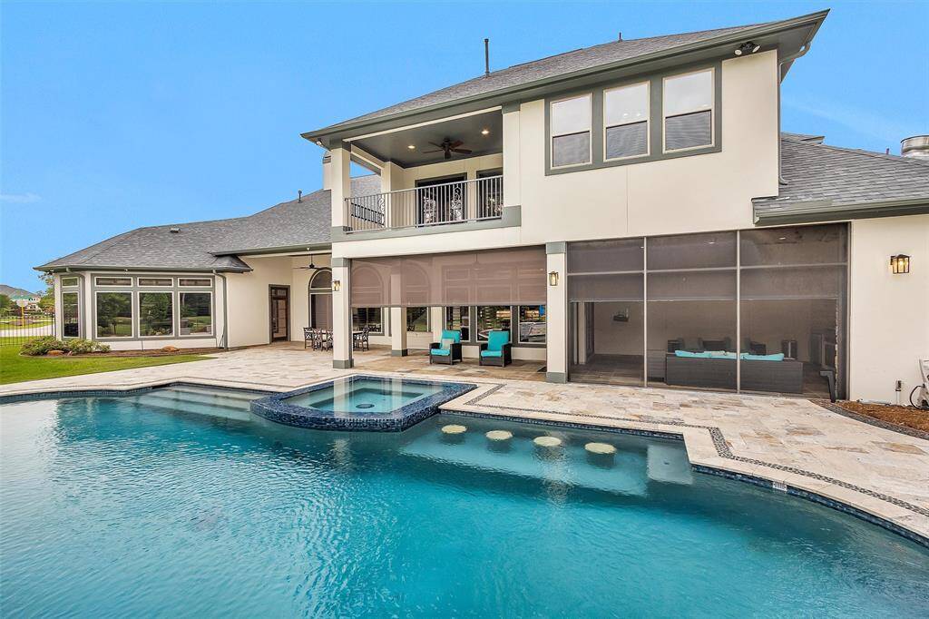 Designed for year-round enjoyment, this resort-style backyard features a pool with a raised spa, submerged bar seating, and a covered patio with remote controlled shades—seamlessly blending comfort, privacy, and luxury.