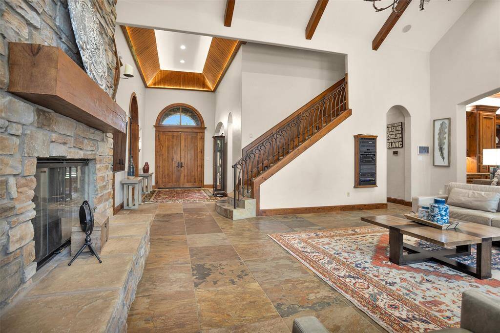 Step into a grand entryway featuring warm slate flooring, soaring ceilings, and double wood doors that welcome you home. This space sets the tone for the entire residence—thoughtfully designed and effortlessly functional. A whole-home Lutron lighting system allows you to control every light with the touch of a button—one to turn everything on, and one to power down with ease.