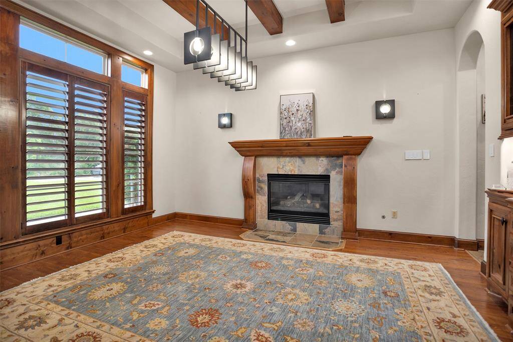 The breathtaking dining room features a cozy gas fireplace, exposed beams, and upgraded lighting for the perfect gathering space.