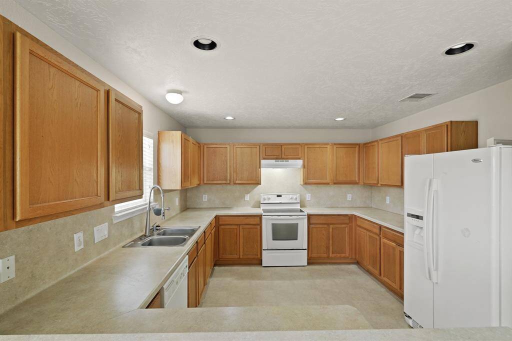The kitchen has wooden cabinetry which is perfect for storage, recessed lighting, and plenty of counter space.