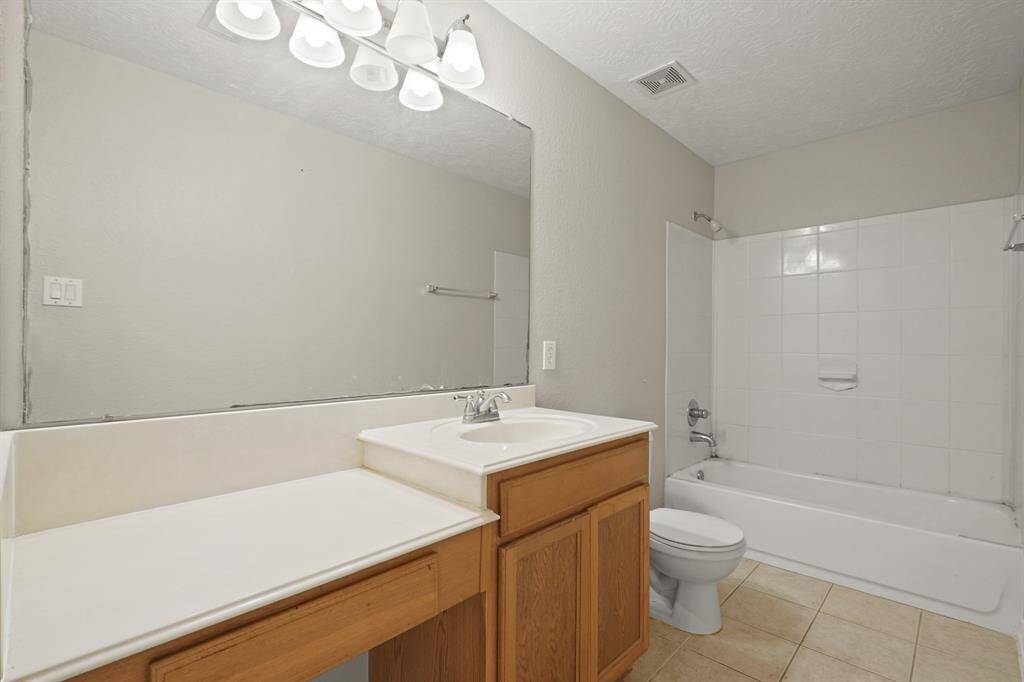 This primary bathroom has a shower/tub combo, a vanity area, and a large mirror.