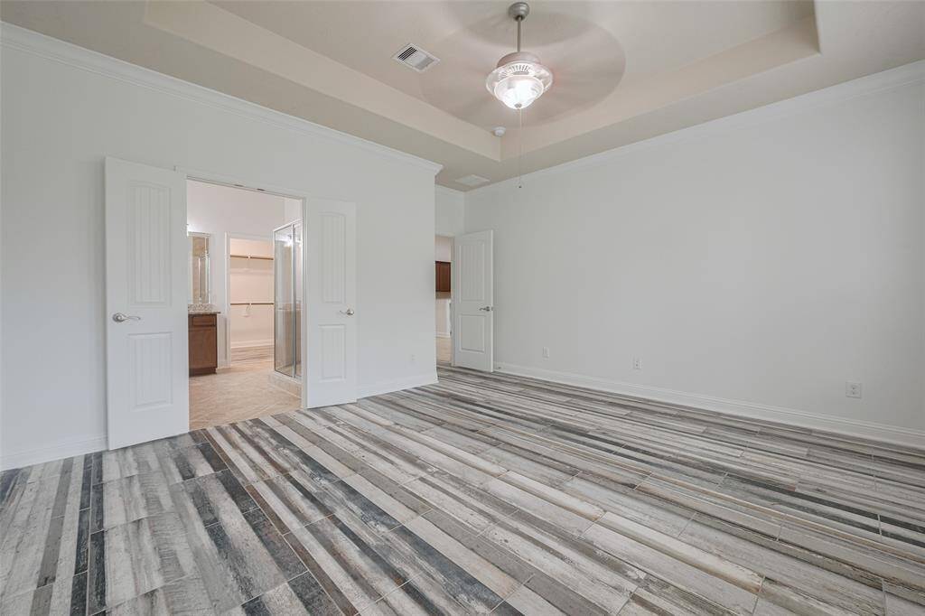 Main bedroom feels expansive with tray ceiling and soft light.