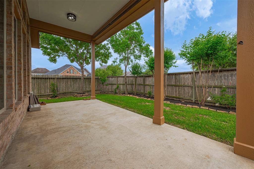 Covered patio overlooks green lawn and garden beds.
