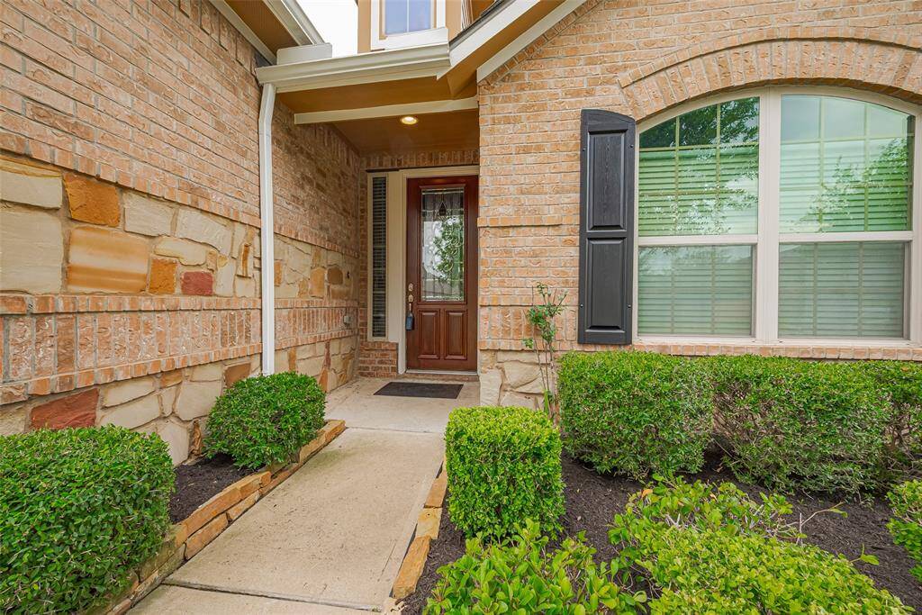 Recessed entry framed by greenery and a tidy walkway.