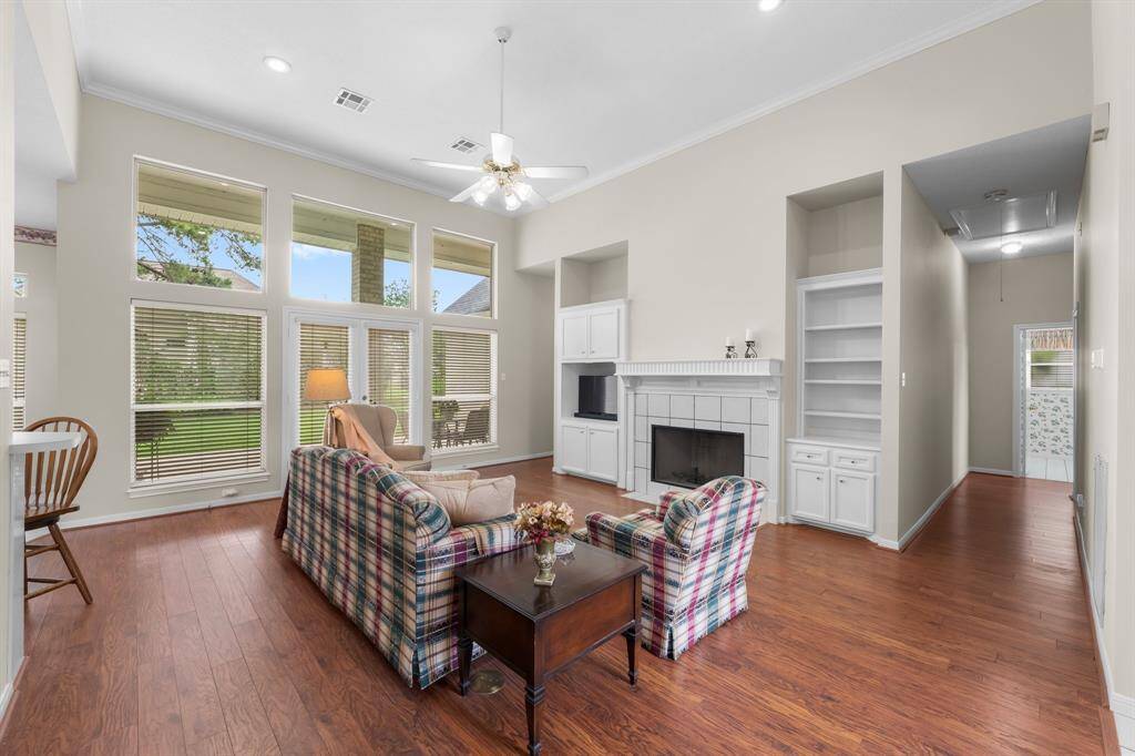 Freshly Painted Bright and spacious living room with high ceilings, large windows, and wooden floors. Features a cozy gas log fireplace, built-in shelving, and an open layout.