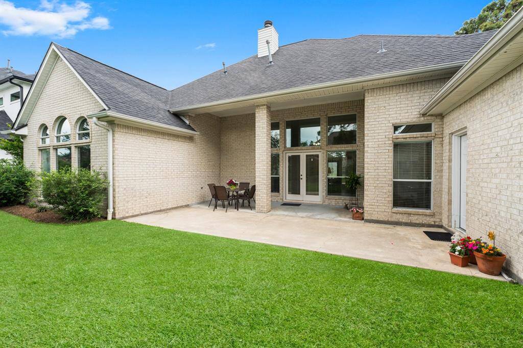 Begin your day or unwind in your backyard retreat! Enjoy a spacious backyard with a well-maintained lawn and a large patio area. The house features a light brick exterior, tall windows, and a covered patio with outdoor seating, perfect for entertaining.