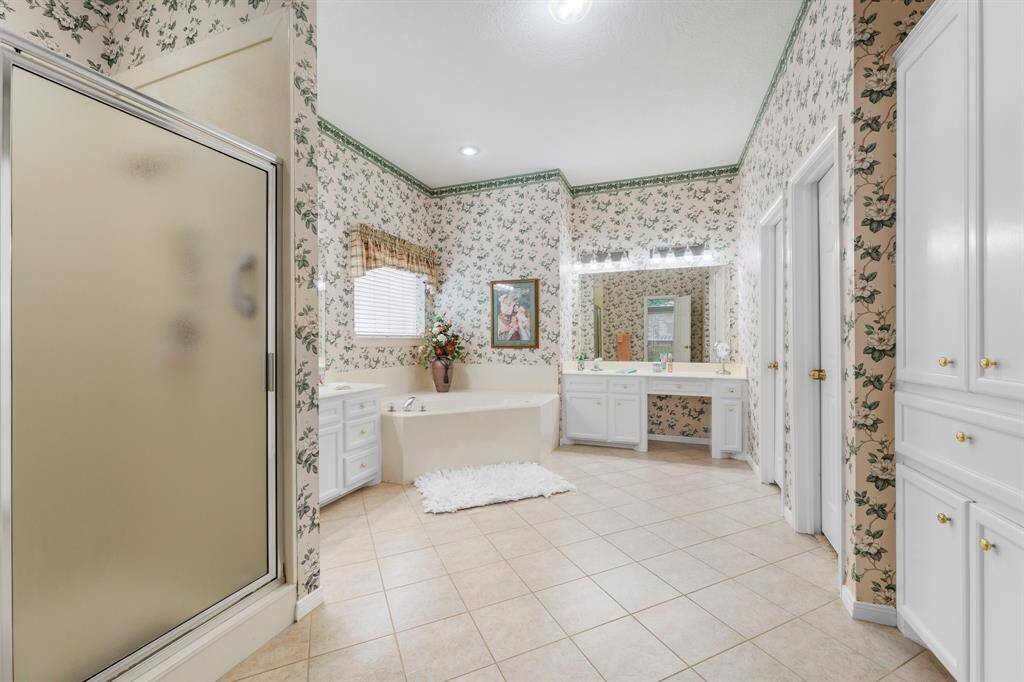 Relax in this oversized primary bath with tiled flooring, separate shower, oversized corner, soaking tub, dual sinks, a vanity area, built ins and walk-in closet.
