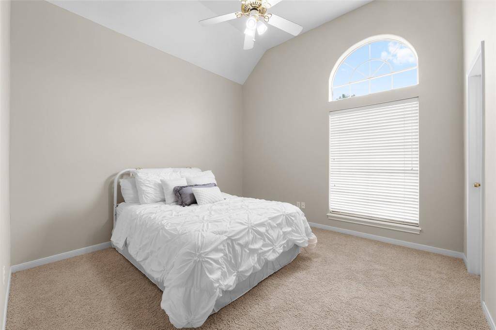 One of the secondary front bedrooms with brand, new neutral, paint, brand, new carpet, high ceilings, walk-in closet, and a ceiling fan.