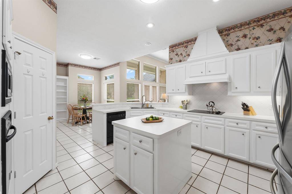 This bright, spacious kitchen features freshly painted real solid wood cabinetry an abundance of countertops, a central island, and undermount lighting; perfect for that chef in you and for entertaining. It has plenty of natural light from large windows and an adjacent dining area, creating a welcoming atmosphere.