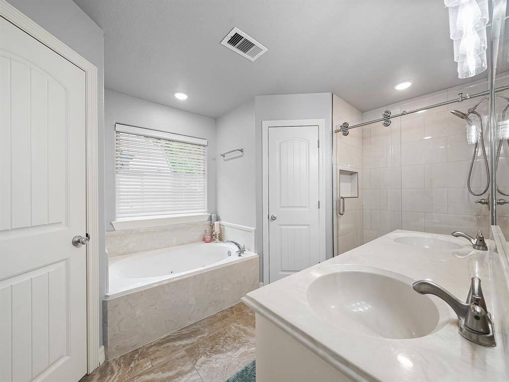 THE RECENTLY UPDATED 1st PRIMARY BATHROOM FEATURES DOUBLE SINKS, HIS & HERS CLOSETS, A SOAKING TUB & A SPACIOUS SHOWER.