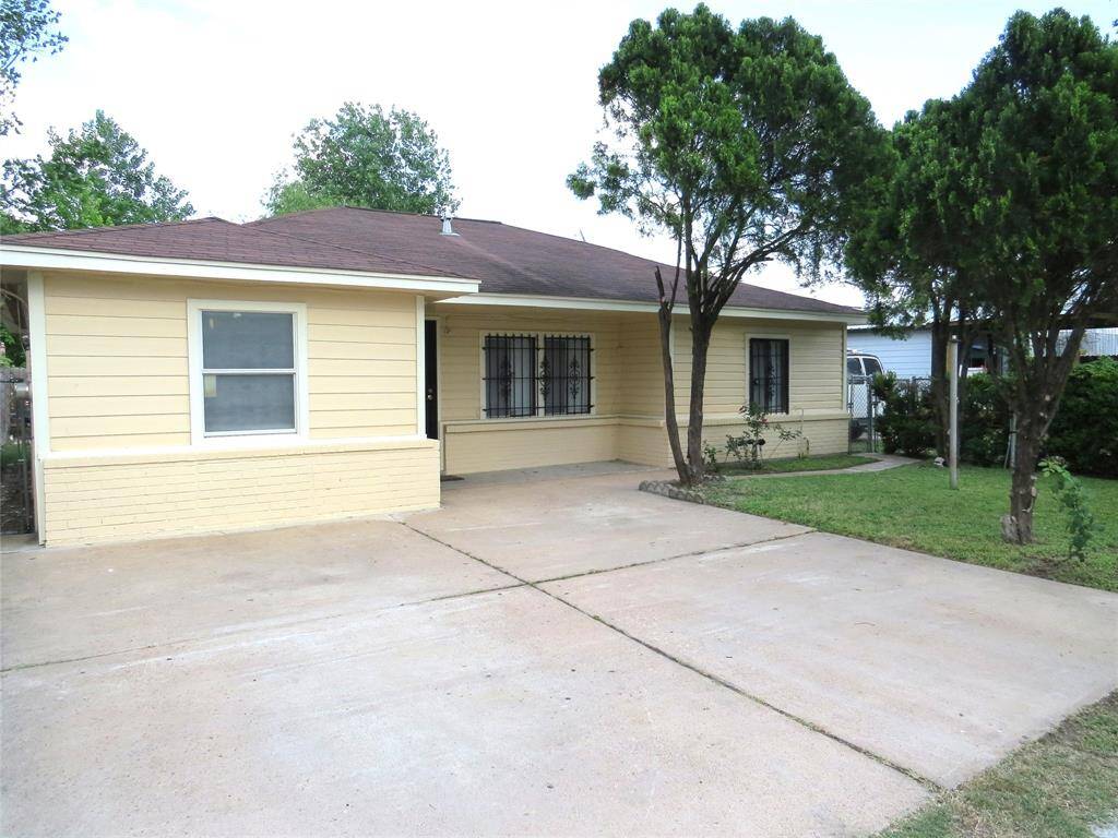 Charming single-story home with a light yellow exterior and a brown roof. The property features a spacious driveway, neatly landscaped front yard, and mature trees providing shade. Ideal for a cozy, welcoming residence.