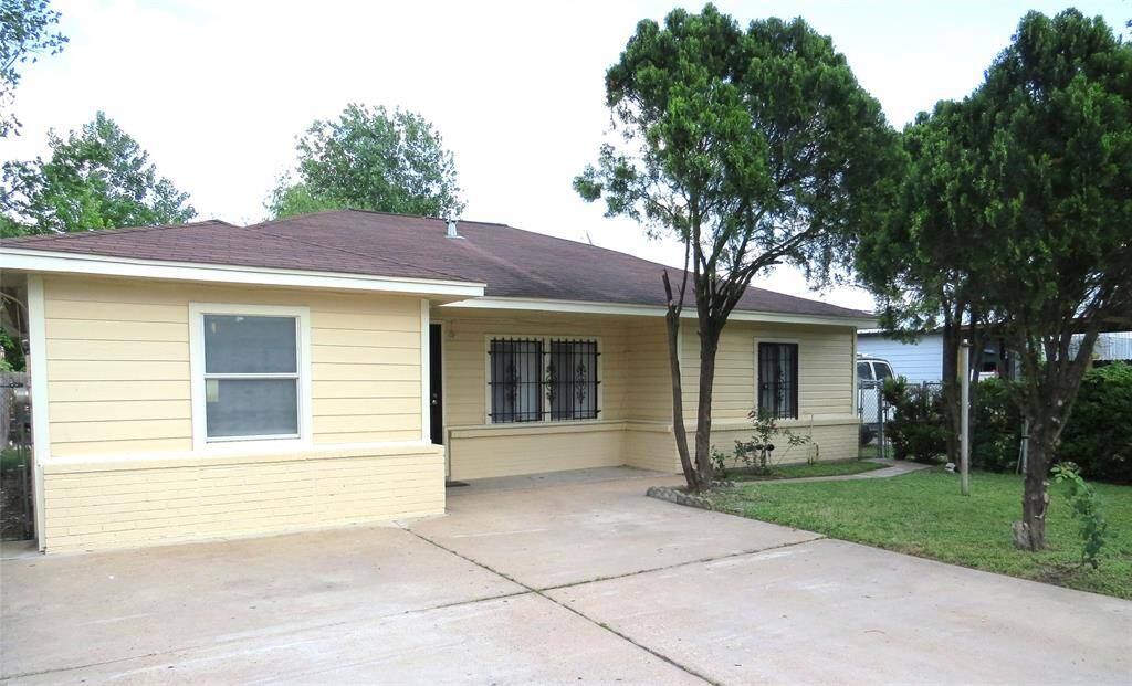 Charming single-story home with a welcoming facade, featuring a paved driveway and a neatly landscaped front yard with mature trees. The exterior is painted in a warm, inviting color, complemented by a well-maintained roof.