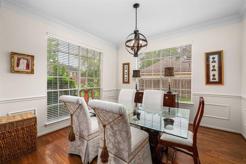 The bright formal dining room boasts large windows, hardwood floors, and elegant wainscoting, with space for a large table and buffet.